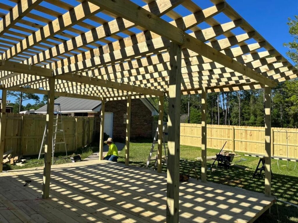 A wood privacy fence in the background of a pergola construction site by Deep South Services LLC in Biloxi, MS.