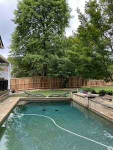 A wood privacy fence installed around a swimming pool area by Hawk Fences LLC in Johns Creek, GA, enhancing safety and privacy.