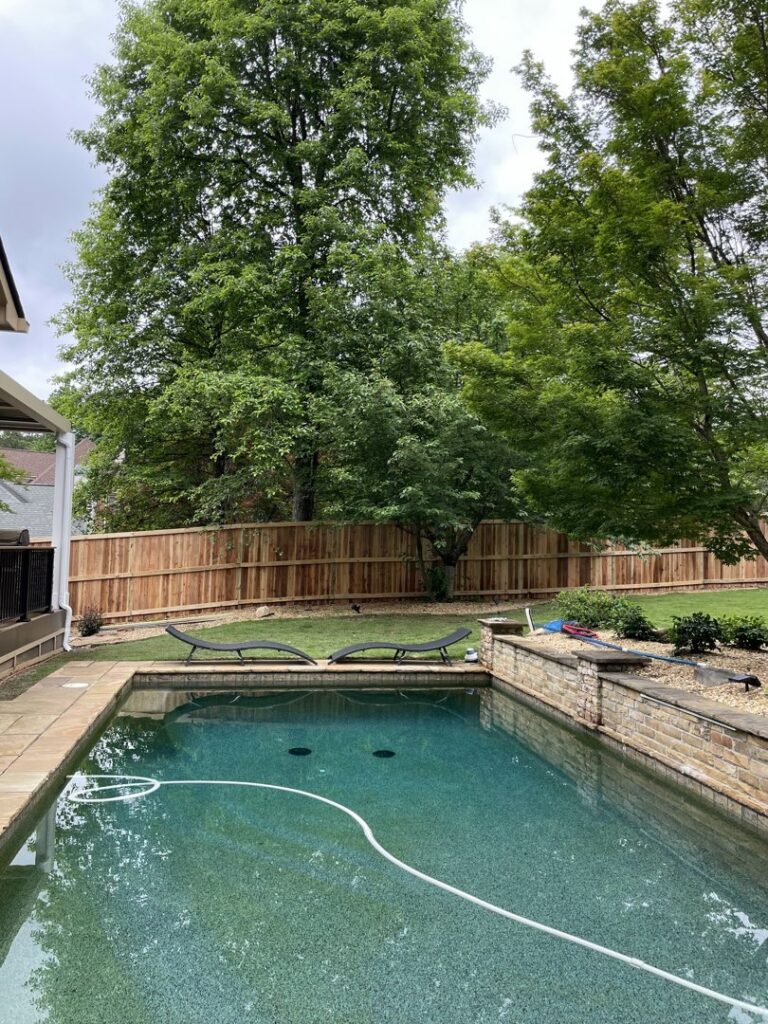 A wood privacy fence installed around a swimming pool area by Hawk Fences LLC in Johns Creek, GA, enhancing safety and privacy.