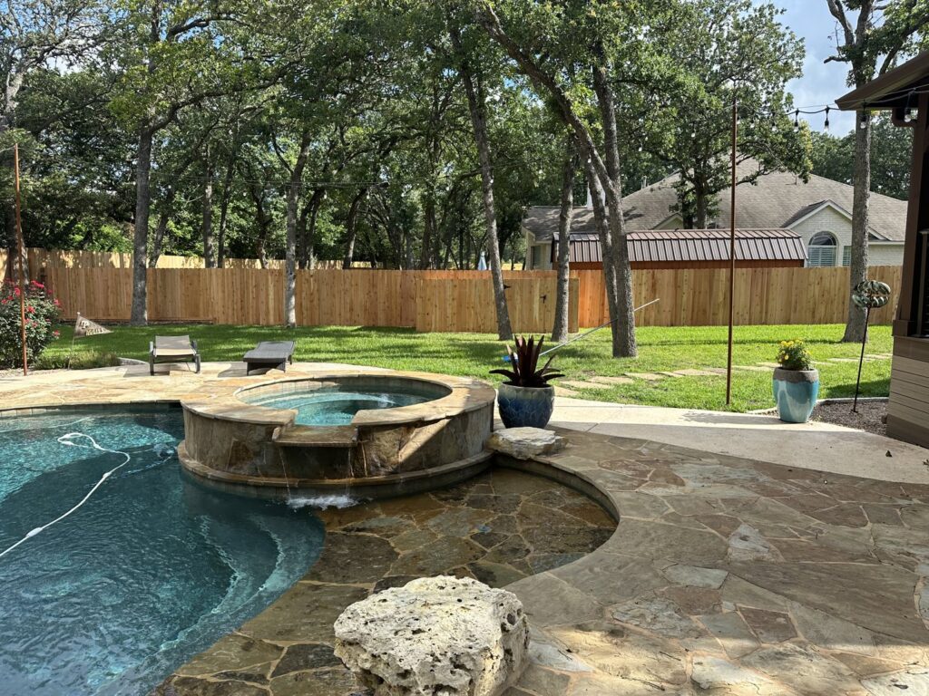 A wood privacy fence installed in a backyard with a pool by Liberty Fence & Stain in San Antonio, TX.