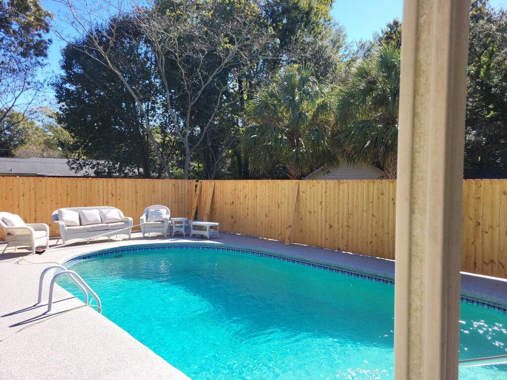 A wooden privacy fence installed around a residential pool area by JB FENCE Brothers company llc in North Charleston, SC.