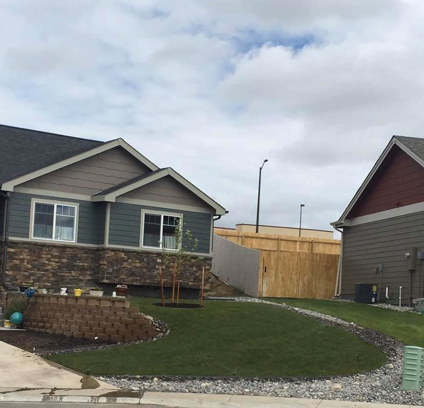 A tall wooden privacy fence installed between residential properties by Highmark Landscaping in Gillette, WY.