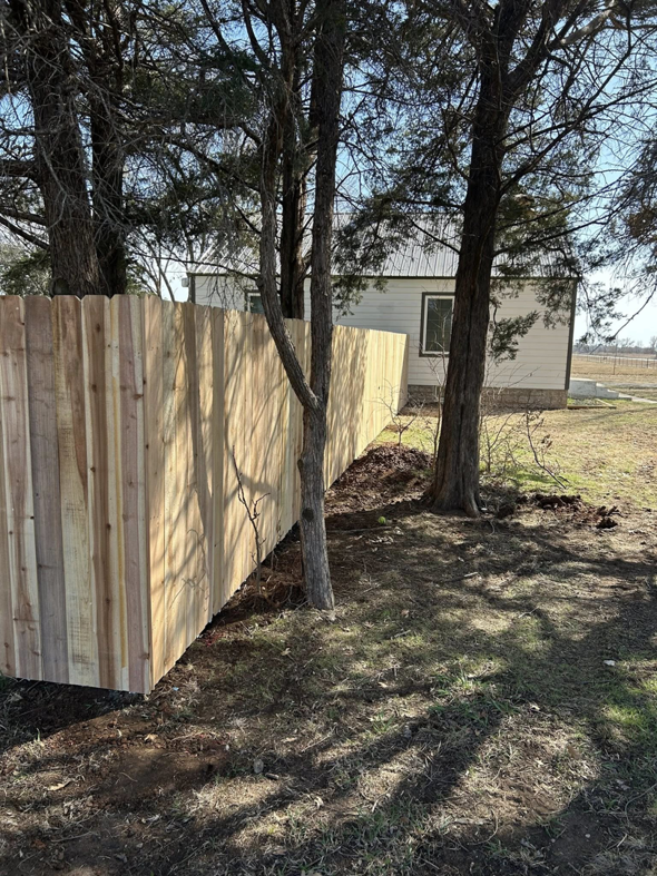 A newly installed wood privacy fence in a rural setting by NC Fencing LLC in Wichita, KS.
