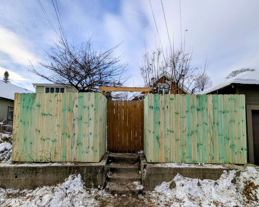 Two sections of new wood privacy fence with a gate opening, installed by Mjölnir Design in Milwaukee, WI.