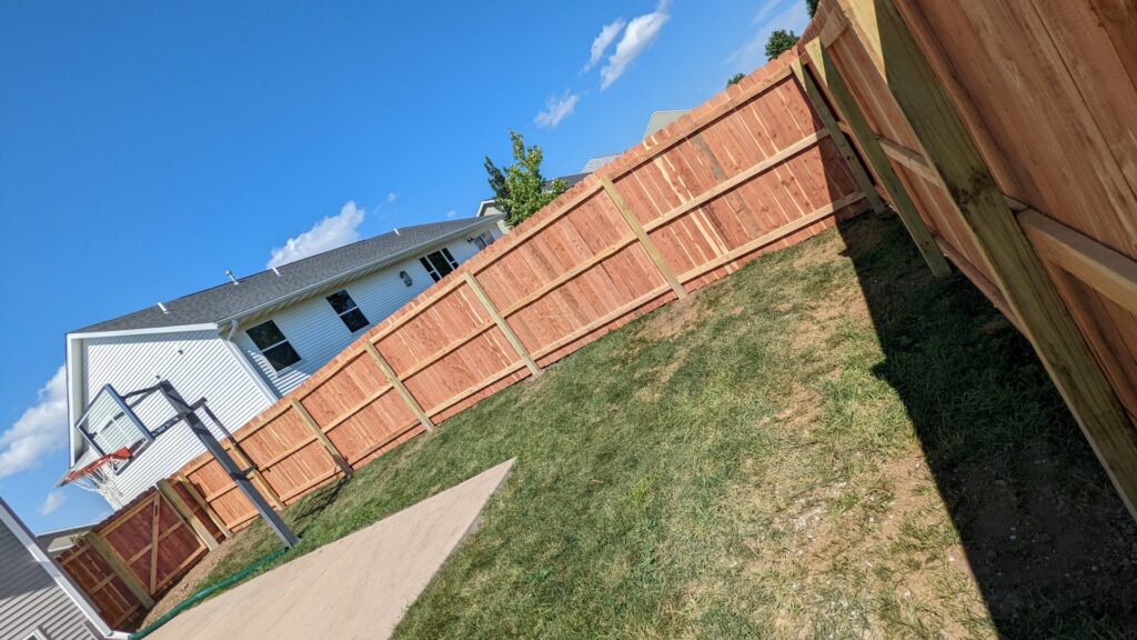 A newly installed wood privacy fence on a sloped residential backyard by Corridor Residential Fencing Co. in Cedar Rapids, IA.