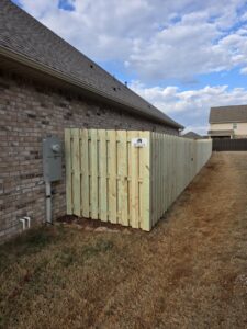 A newly installed wood privacy fence enclosing a utility area next to a house by Alabama's Fencing in Huntsville, AL.
