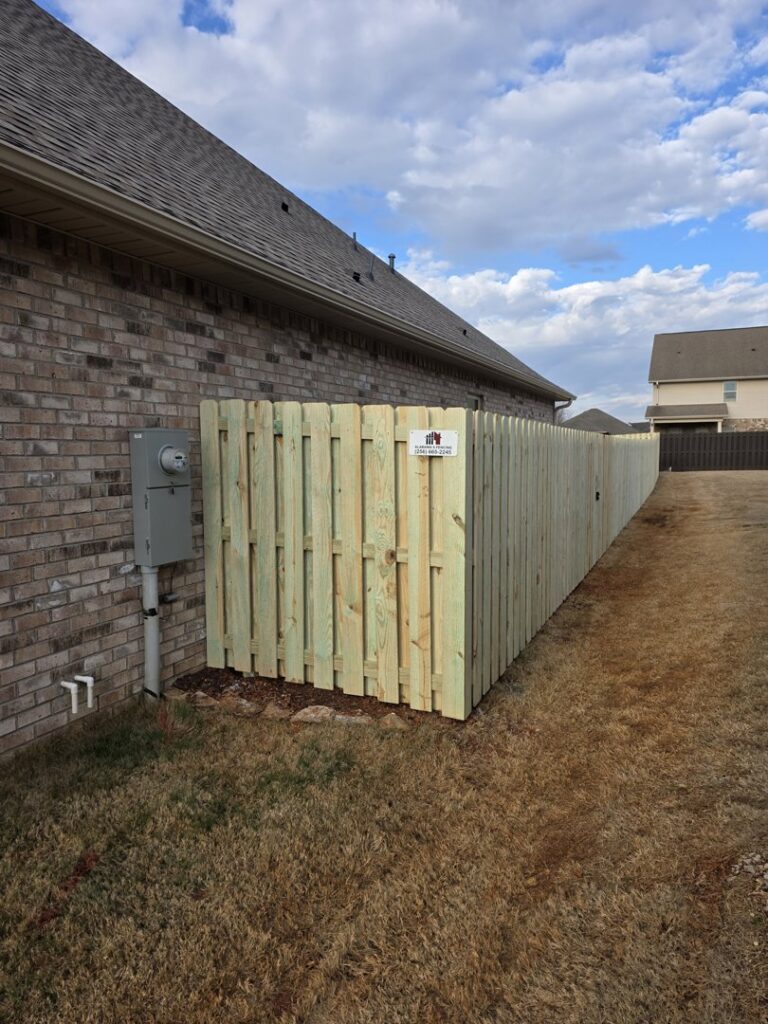 A newly installed wood privacy fence enclosing a utility area next to a house by Alabama's Fencing in Huntsville, AL.