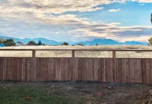 A wood privacy fence with decorative wire mesh panels at the top, installed by R&S Fencing & Design LLC in Denver, CO.