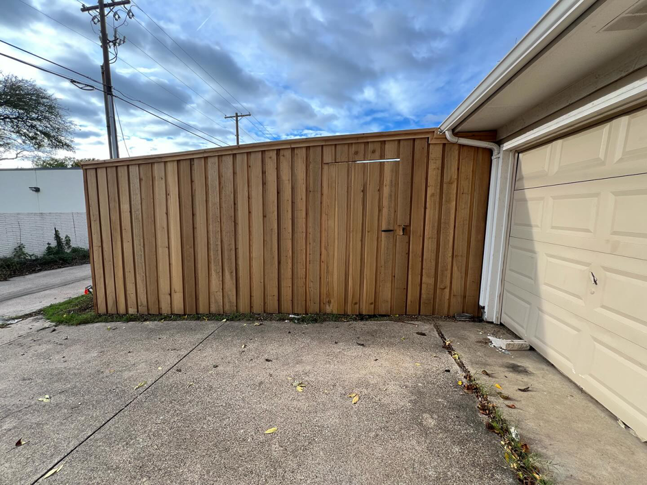 A newly installed wooden privacy fence with a small access door next to a garage by True Ways Services LLC in Mesquite, TX.