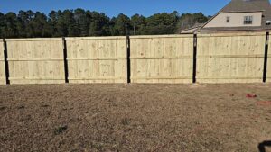 A new wood privacy fence with black posts installed in a backyard by Fayetteville Fence Pros in Fayetteville, NC.