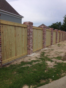 A custom wood privacy fence featuring decorative brick pillars installed by Custom Fence Builders in Gulfport, MS.