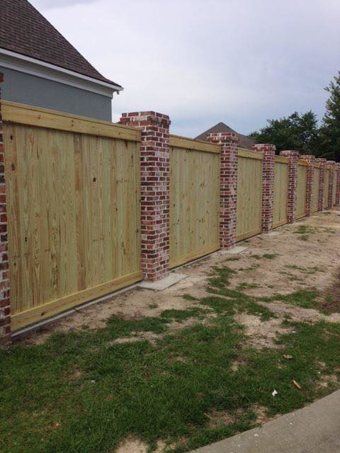 A custom wood privacy fence featuring decorative brick pillars installed by Custom Fence Builders in Gulfport, MS.