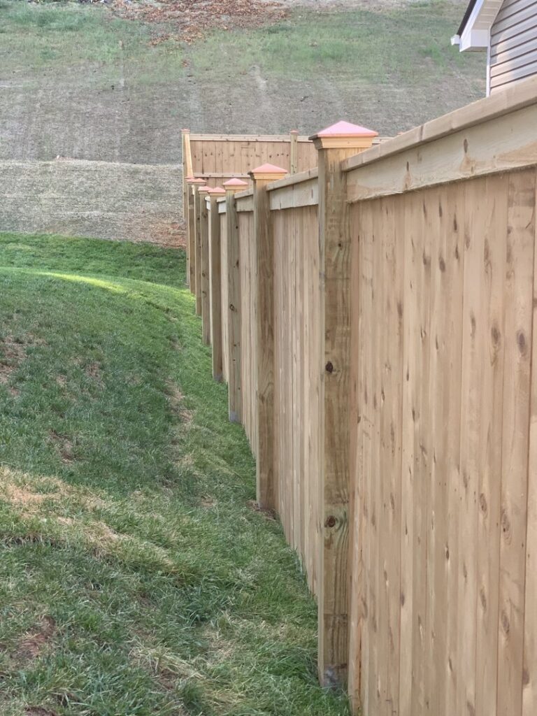 A wood privacy fence with decorative post caps installed by Escamilla Fence Co. in Knoxville, TN