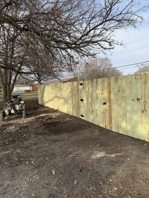 A newly installed wood privacy fence featuring decorative hinges by Heath's Outdoor Services LLC in Champaign, IL.