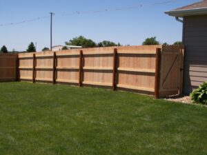 A newly installed wood privacy fence with a gate in a residential backyard by American Fence Company of Norfolk in Grand Island, NE.