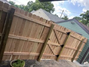 A newly installed wood privacy fence with a gate next to a house by American Fence Company - Omaha in Omaha, NE.