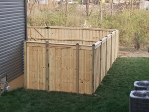 A new wood privacy fence with a gate installed around AC units by Veteran Fence in North Royalton, OH.