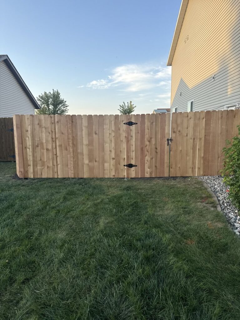 A wooden privacy fence with a gate installed in a residential backyard by Aces Deck and Fence in Fargo, ND