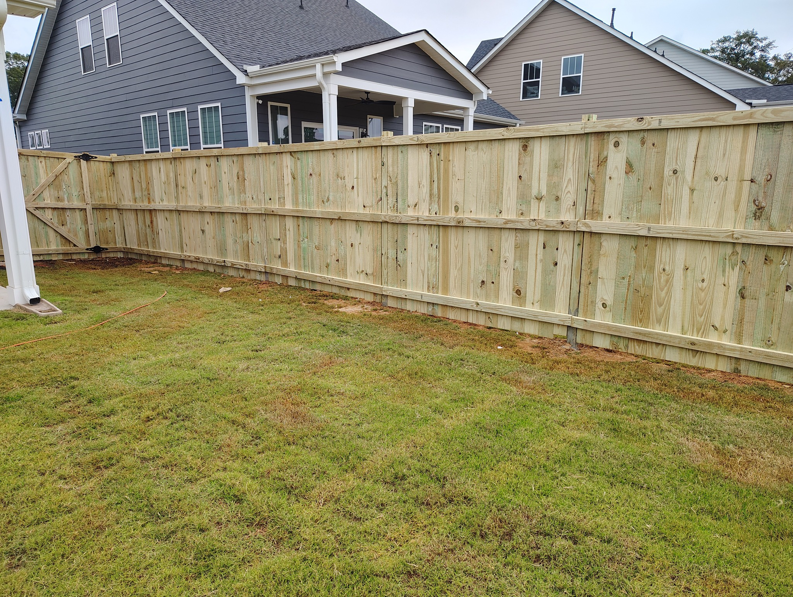 A wood privacy fence with a gate at a corner of a backyard, installed by Maine Wood Fencing & more in Greenville, SC.
