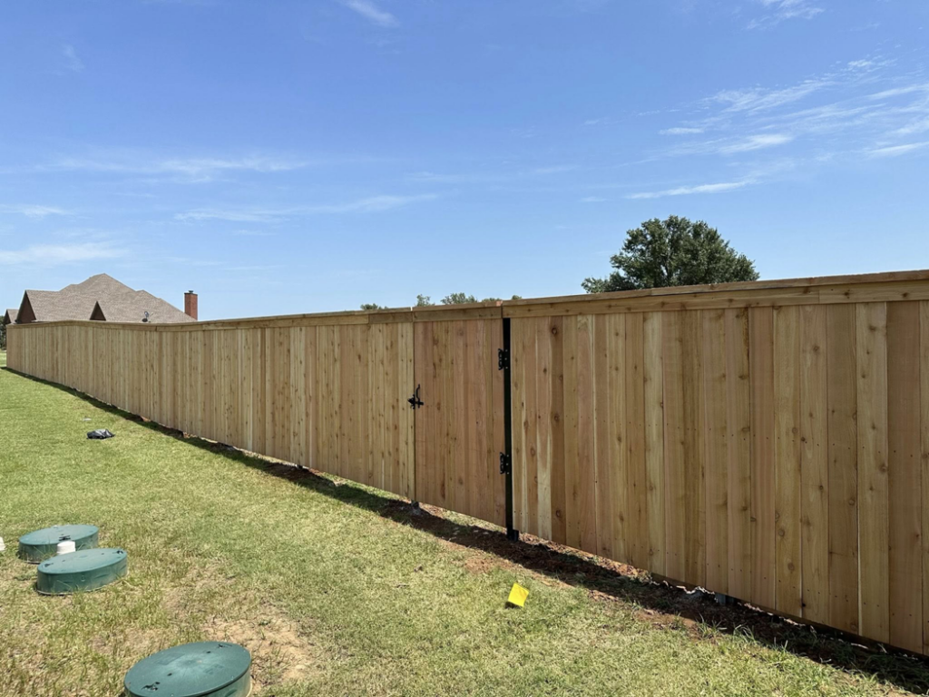 A newly installed wood privacy fence featuring a gate by DB Construction in Fort Smith, AR.