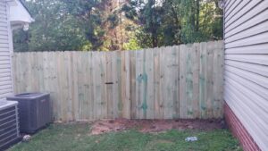 A wood privacy fence with a gate next to a house by Escamilla Fence Co. in Knoxville, TN