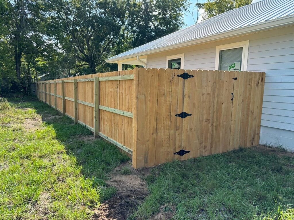 A newly installed wood privacy fence featuring a gate, providing security and aesthetics from Exacta FENCE LLC in Jacksonville, FL.