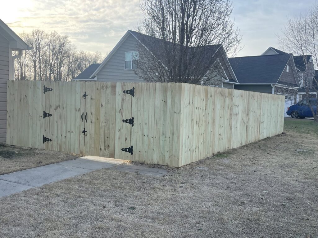 A new wood privacy fence with a double gate installed around a residential property by Fencingphd.nc in Fayetteville, NC.
