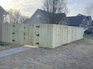A new wood privacy fence with a double gate installed around a residential property by Fencingphd.nc in Fayetteville, NC.