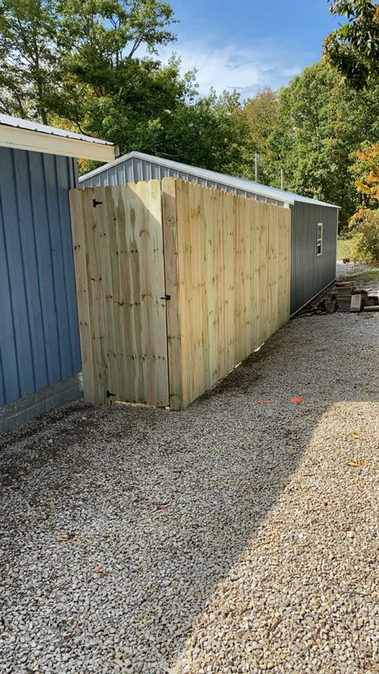 A newly installed wood privacy fence with a gate by Higdon's fence install & repair in White Mills Junction, KY