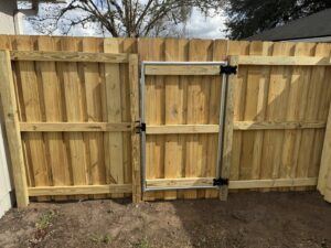 A newly installed wood privacy fence with a sturdy metal-framed gate by Fence Nation LLC in Jacksonville, FL.