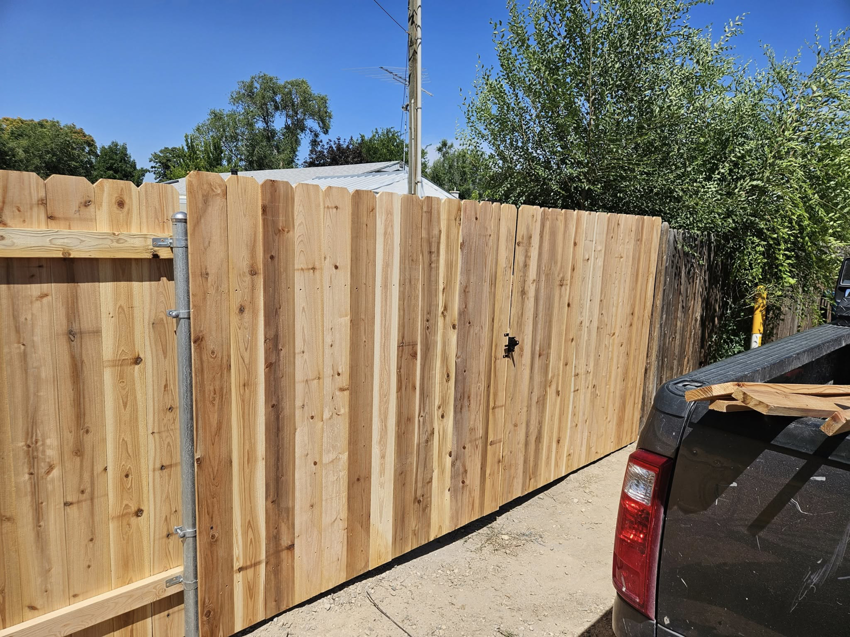 A newly installed wood privacy fence with a sturdy gate, ready for use, completed by Regan Fencing & Services in Nampa, ID.