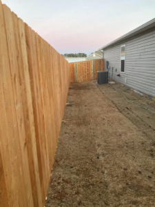 A newly installed wood privacy fence with a gate along a residential property by Best Fences LLC in Springdale, AR.