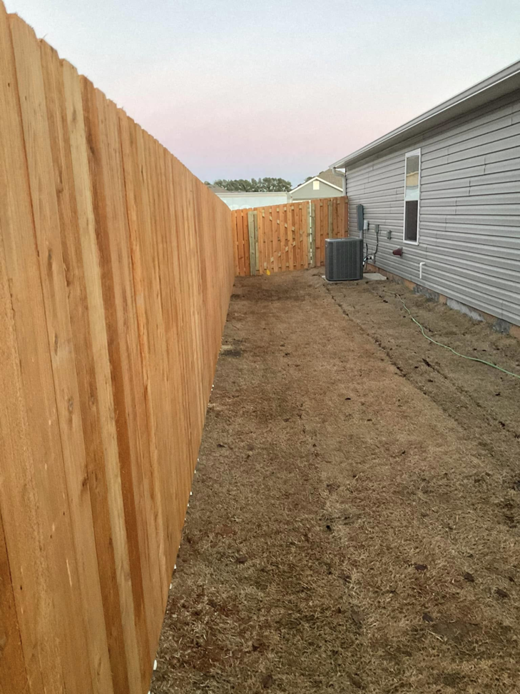 A newly installed wood privacy fence with a gate along a residential property by Best Fences LLC in Springdale, AR.