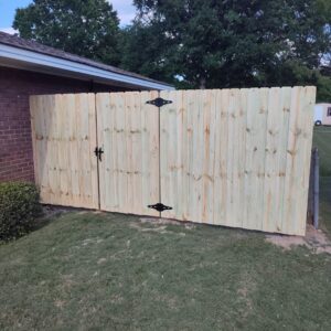 A newly installed wood privacy fence with a gate, enhancing a home's perimeter by The Fence Dudes in Birmingham, AL.