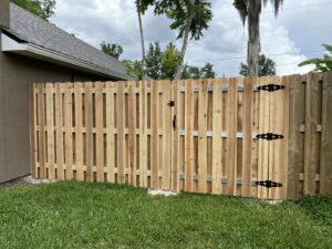 A newly installed wood privacy fence with a gate and decorative hinges by Top Fence LLC in Jacksonville, FL.