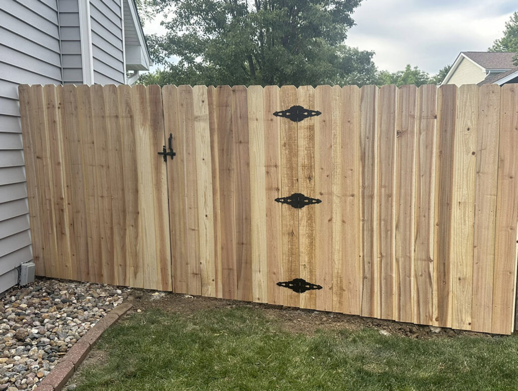 A custom wood privacy fence with a gate and decorative black hardware, installed by Top Rail Fence Des Moines in West Des Moines, IA.
