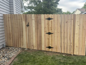 A custom wood privacy fence with a gate and decorative black hardware, installed by Top Rail Fence Des Moines in West Des Moines, IA.