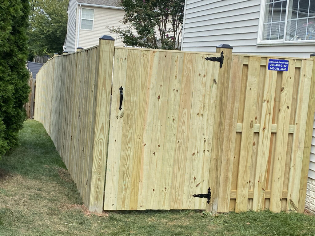 A newly installed wooden privacy fence with a gate by Universal Fence LLC in Drainesville, VA.