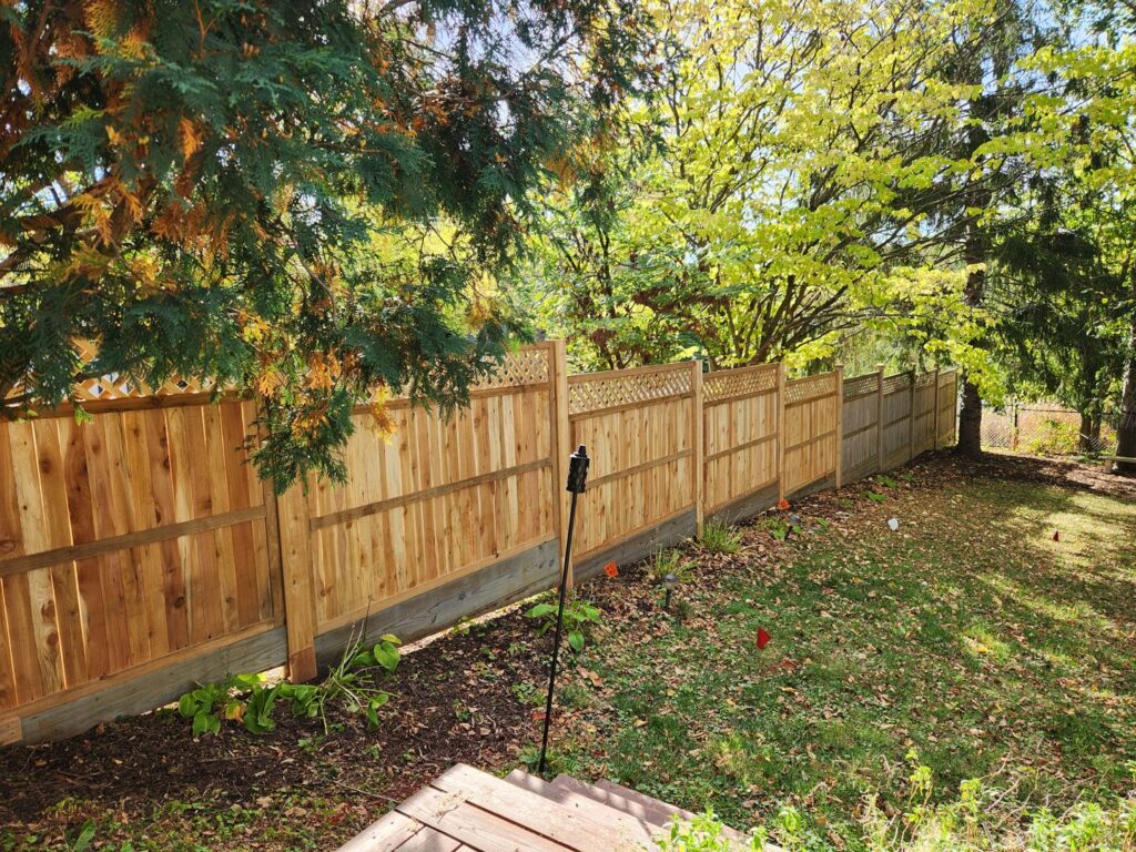 A newly installed wood privacy fence with a decorative lattice top in a backyard by Corridor Residential Fencing Co. in Cedar Rapids, IA.