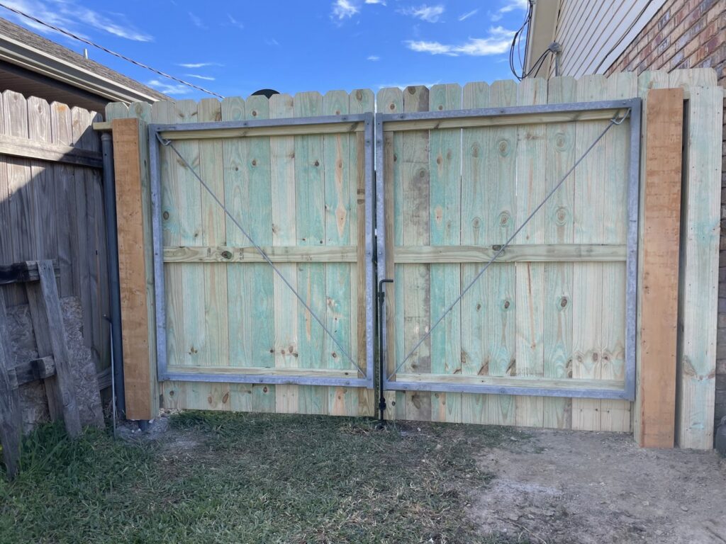 A wood privacy fence with a robust metal-framed double gate, installed by 985 Fence, LLC in Schriever, LA.