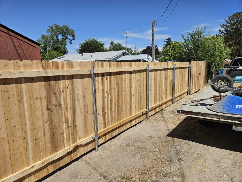 A newly constructed wood privacy fence featuring sturdy metal posts and a gate, installed by Regan Fencing & Services in Nampa, ID.