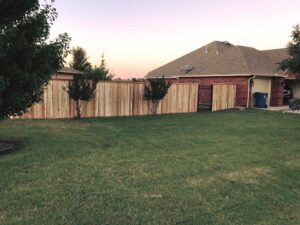A wood privacy fence with a small metal gate installed by ProScape Outdoor Construction LLC in Norman, OK.