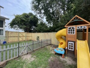 A backyard featuring a new wood privacy fence and a grey picket fence with a gate, installed by Charleston Fencing Services in Moncks Corner, SC.