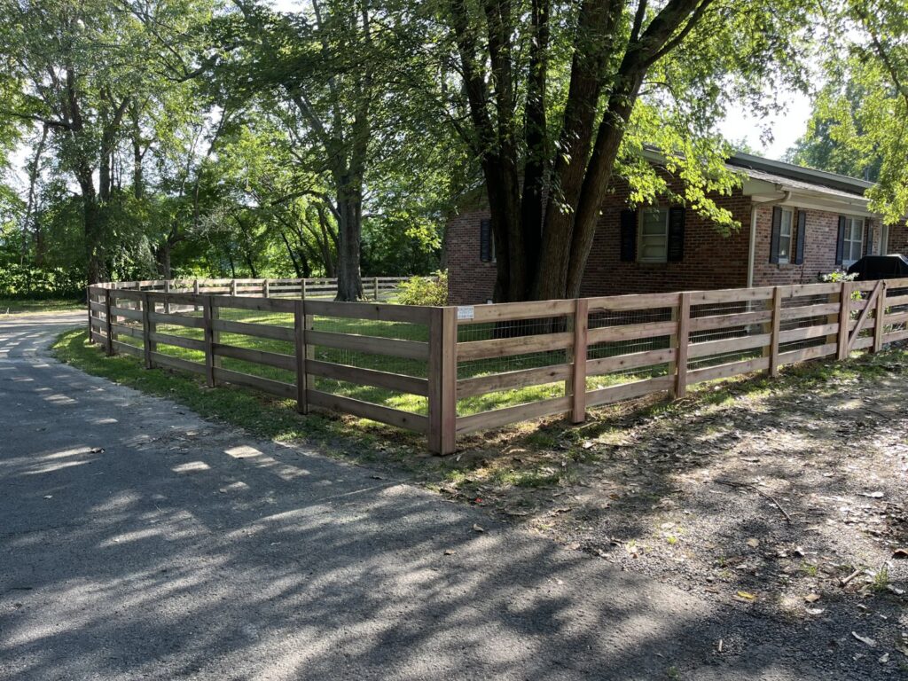 A wood rail fence with wire mesh installed around a residential yard by Frontier Fence LLC Bowling Green,Ky