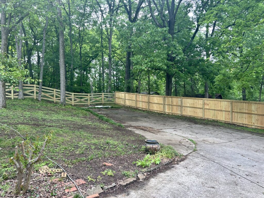 A combination of wood split rail and privacy fencing in a wooded area by Fenceworks of Middle Tennessee in Nashville, TN.