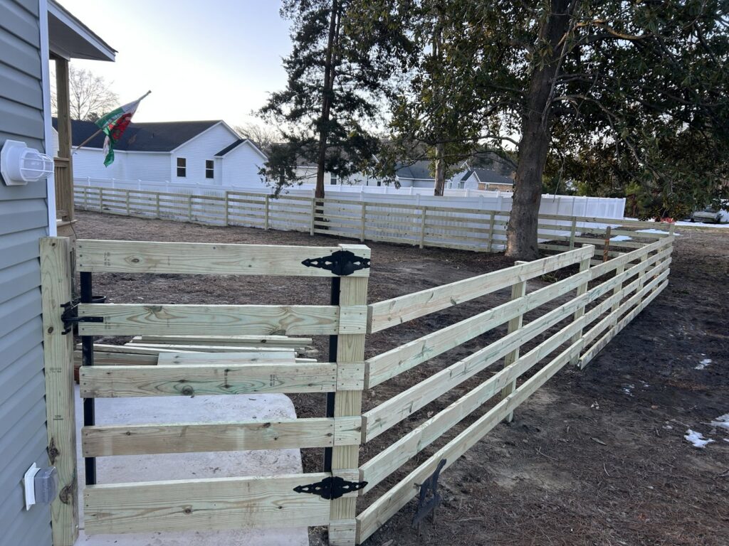 A new wood split-rail style fence with a gate installed by Sea Level Fence in Harbinger, NC