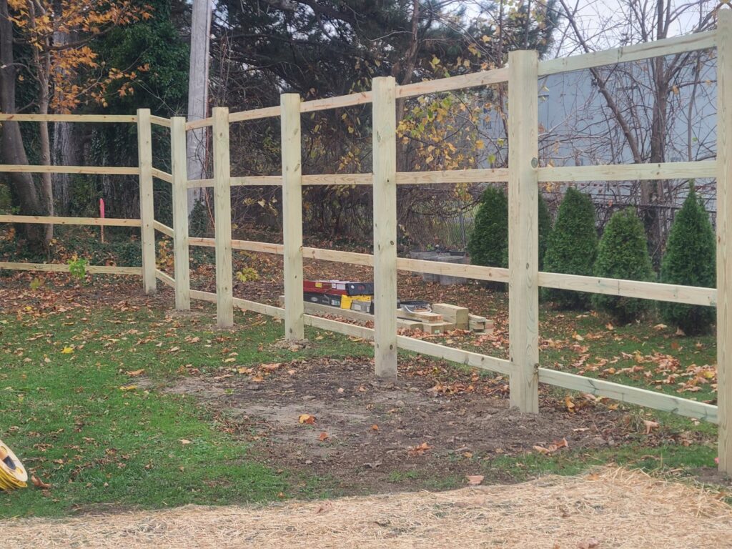 A newly installed wood split-rail fence by Camp Carlson Fencing in Rochester, NY, providing a rustic boundary.