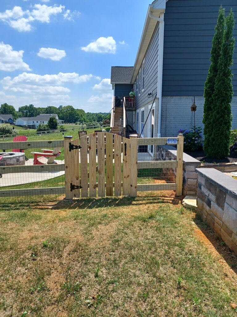 A wooden split rail fence with wire mesh and a gate, installed next to a patio by A Freedom Fence in Martinsburg, WV.