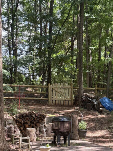 A charming wood split-rail fence with wire mesh and a matching gate in a wooded backyard by Cavitt Fencing in Concord, NC.