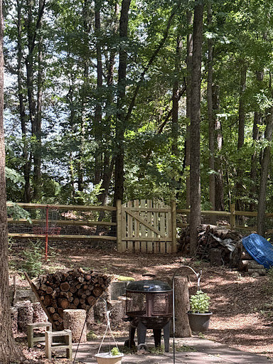 A charming wood split-rail fence with wire mesh and a matching gate in a wooded backyard by Cavitt Fencing in Concord, NC.